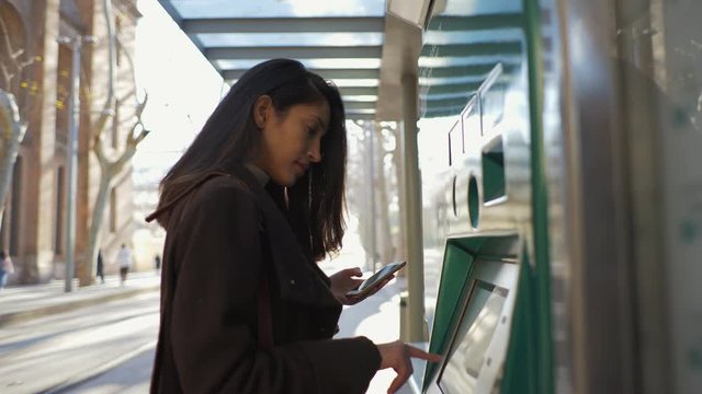 Woman using ticket machine at tram stop