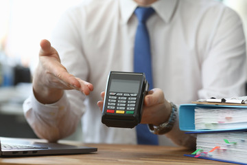 Man holds his hand wireless terminal for payment. Bank employee offers to install a wireless terminal for business. Providing customers with more convenient way to make settlements