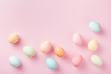 Pastel Easter eggs on pink background top view. Flat lay style.