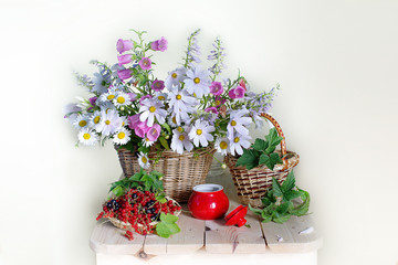 A bouquet of wild flower in a basket and ripe berries on the table .