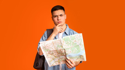Puzzled backpacker holding city map, planning journey