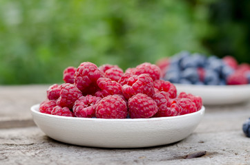 Still life with a blueberries and raspberries on an old wooden table, at the garden. Rural natural food style.