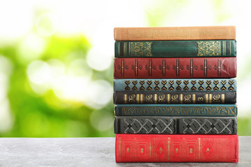 Naklejka premium Collection of different books on table against blurred green background, space for text