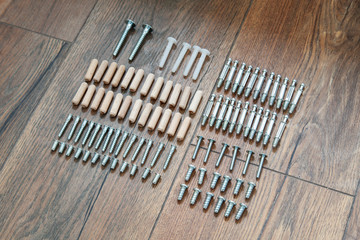 Top view arrangement group of parts (dowel, bolt, screw) for furniture assembly on wooden floor. Tools for assembling furniture. DIY concept.