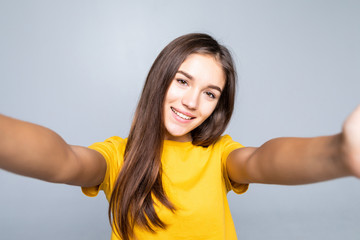 Naklejka na ściany i meble Portrait of a smiling cute woman making selfie photo on phone isolated on a white background