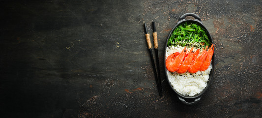 Asian food. Rice, shrimp and salad Chuka in a black bowl. Rustic style. Top view. Free space for your text.