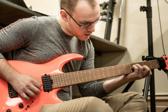 Male hispanic-caucasian high school student playing electric guitar in music classroom during rehearsal