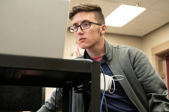 Male High School Student and Sound technician listening to playback during rehearsal in music classroom