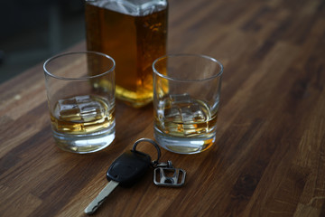 Car key lies on table next to bottle alcohol. Permissible rate alcohol while driving. Drivers are tempted to drink strong drinks. Identify drunken motorists. Drunk driving. Checking for intoxication