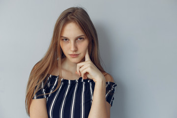 Beautiful girl in a studio. Stylish girl near blue wall. Lady shows her emotions/