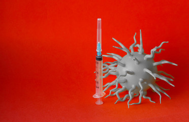 A gray bulk virus molecule and a syringe with a sharp needle on a red background. Selective focus....