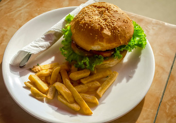 Burger on a plate on a table in the street at a resort.