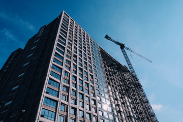 Obraz premium Construction of a multi-storey building. Construction scaffolding and crane. Brick and glass.