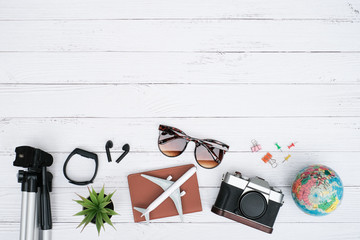 Flat lay vacation planing and traveling holiday concept on white wooden table background with plane is on passport, sunglasses and camera, Tripod and accessories, Top view with copy space