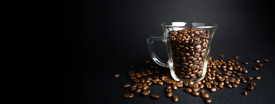 roasted coffee beans in the glass on black background