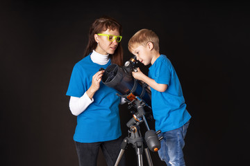Fototapeta na wymiar Mom and son are studying a large refractory telescope.
