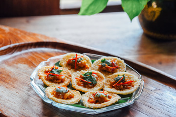 Crispy rice cake and pork and shrimp dipping in plate on wood table. thai food