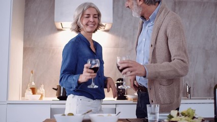 Slow motion shot of mature couple drinking red wine in kitchen at home - Powered by Adobe