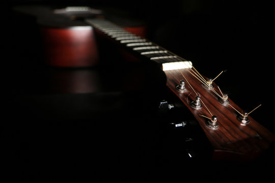 A shaded picture of a guitar. It lies in the dark with only a part visible under small amount of light.