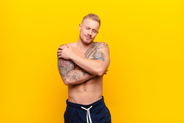 young strong blonde man feeling in love, smiling, cuddling and hugging self, staying single, being...