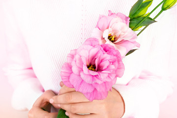 Beautiful woman's hands with nude manicure hold eustoma purple flower. White sweater. Pink blooming spring plant
