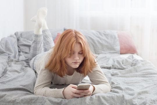 teenager girl with smartphone on bed