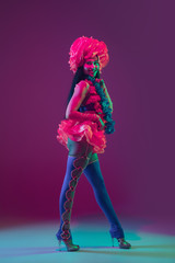 Blossom. Hawaiian brunette model on purple studio background in neon light. Beautiful women in traditional clothes smiling, dancing and having fun. Bright holiday's, celebration colors, festival.