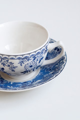 Ceramic saucers with a cup for tea in blue with flowers. New luxury elegance dinnerware on a isolated white background. Trendy plate. Flat lay view.