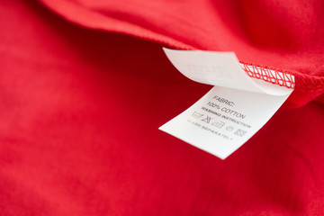 White laundry care washing instructions clothes label on red cotton shirt