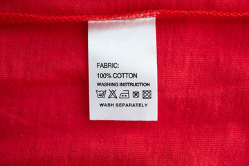 White laundry care washing instructions clothes label on red cotton shirt