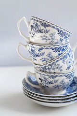 Ceramic saucers with a cup for tea in blue with flowers. New luxury elegance dinnerware on a isolated white background. Trendy plate. Flat lay view.
