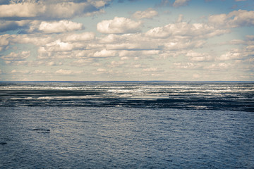 Fototapeta na wymiar Spring melting ice on the river. Against the background of blue sky and clouds.