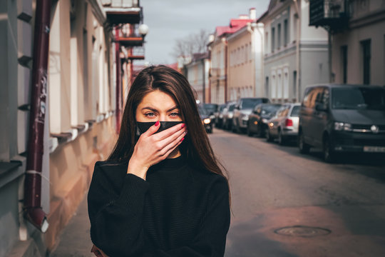 Girl, Young Woman In Protective Sterile Medical Mask On Her Face Looking At Camera Outdoors, On Asian Street Show Palm, Hand, Stop No Sign. Air Pollution, Virus, Chinese Pandemic Coronavirus Concept.