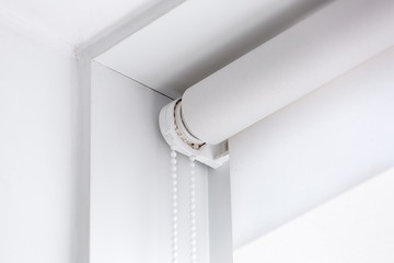 white rolled textile blinds on the window in a room corner, object of protection against sunlight...