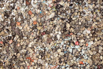 Many chewed chewing gums of different colors are glued to the surface next to each other