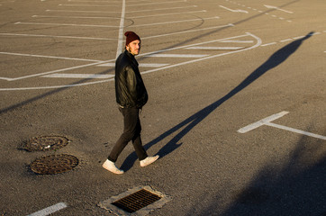 young cool man dressed in leather walking on the asphalt