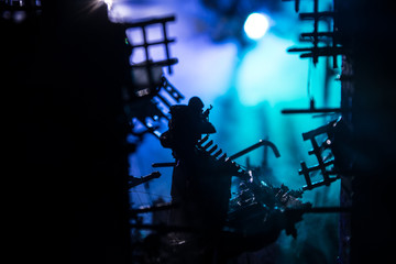 Army sniper with large caliber rifle standing in the fire and smoke. War Concept. Battle scene on war fog sky background, Fighting silhouettes Below Cloudy Skyline at night. City destroyed by war