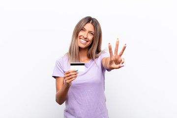 young pretty woman smiling and looking friendly, showing number three or third with hand forward,...