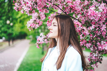 Young girl looks away at a blossoming pink apple tree.
