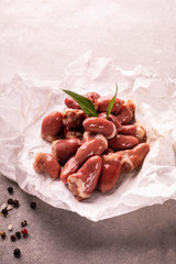 Raw chicken hearts on a paper on stony worktop. Poultry, giblets.