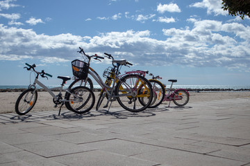 group of bicycles parked on the coast of the Mediterranean Sea, in Cambrils, with a beautiful cloudy sky, family bike scene with copy space