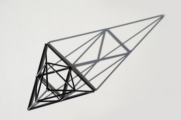 Decorative black pyramid with contrasting shadows on a white background. Flat Lay Style