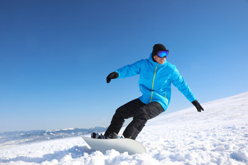 Fototapeta na wymiar Man snowboarding on snowy hill. Winter vacation