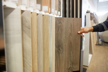 Man chossing wood floor from the sampler, swatch for his new apartment, household furnishing