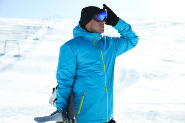 Male snowboarder on snowy slope in mountains. Winter vacation