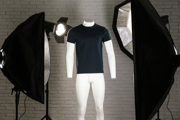 Stylish clothes on ghost mannequin and professional lighting equipment in modern studio. Fashion...