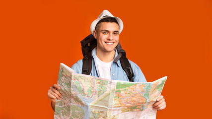 Joyful hiker with big backpack holding map