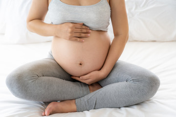 Close up of pregnant woman on white bed