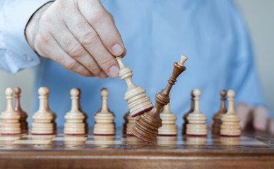 Strategy concept, hand of businessman moving wooden chess figure in play, management or leadership competition success background.