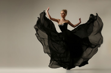 A female ballet dancer in a long black valtier, with a very wide skirt, jumps and dances in the...